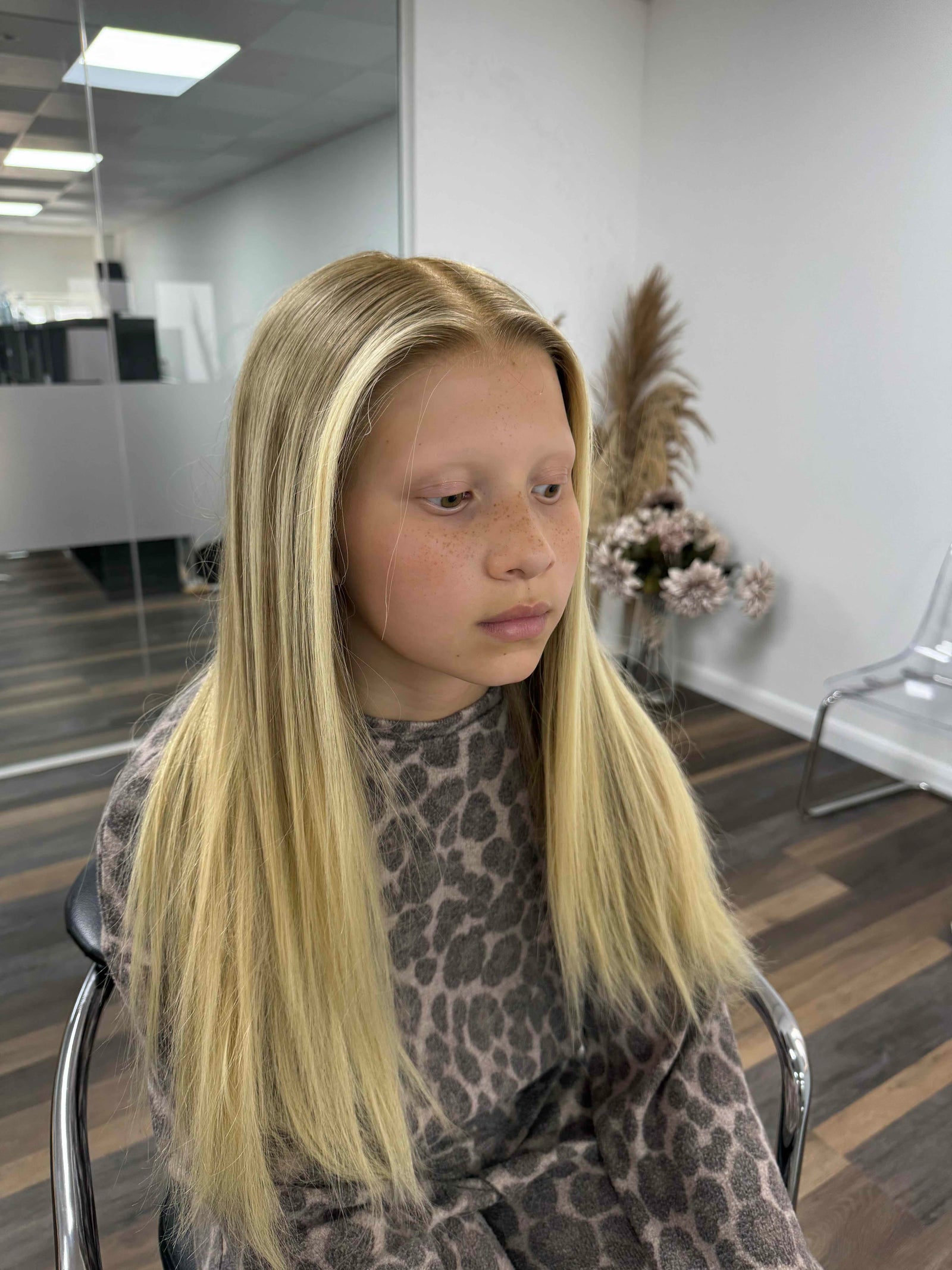 Child wearing a long blonde straight human hair wig, styled naturally,
against a white background – Nuola Wigs.